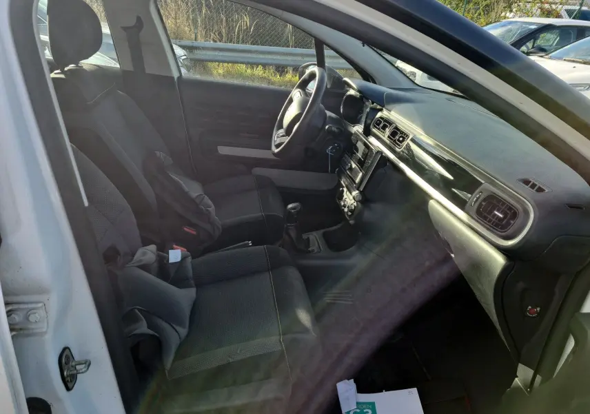 Vue intérieure côté conducteur de la Citroën C3 Société blanche 2020, montrant les sièges et le tableau de bord noir.