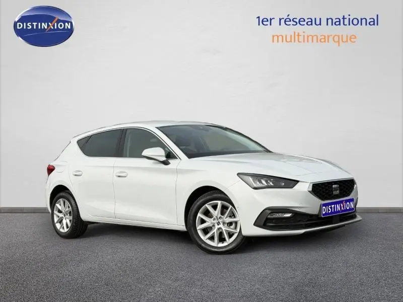 Vue 3/4 avant droite d'une SEAT Leon blanche Nevada métallisée avec jantes alu et calandre noire.