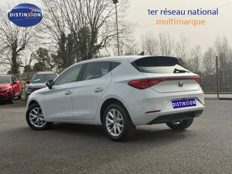 Vue 3/4 arrière droite d'une SEAT Leon 2025 blanche Nevada métallisée avec jantes alu et feux arrière LED.