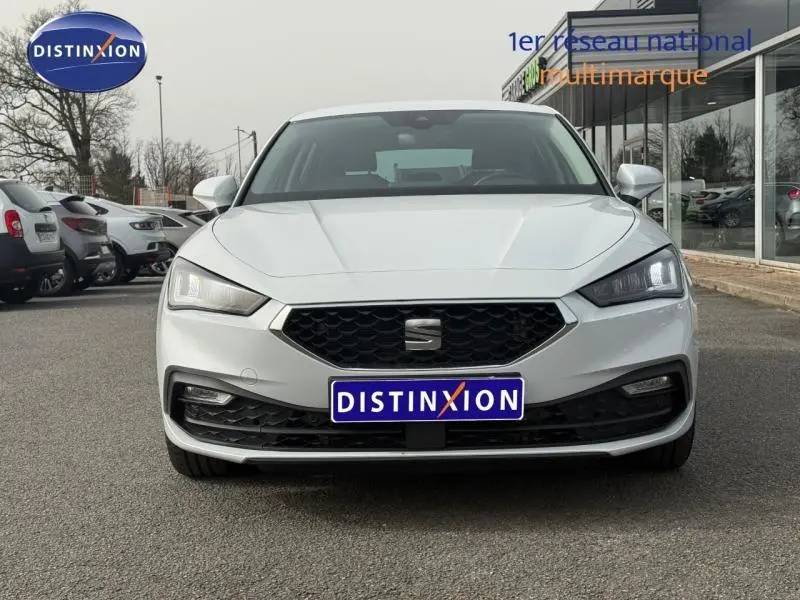 Vue avant d'une SEAT Leon 2.0 TDI blanche Nevada métallisée, avec calandre noire et feux LED allumés.
