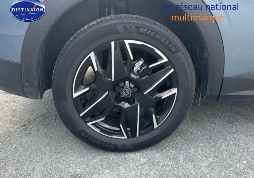 Gros plan sur la roue avant gauche avec jante alu noire et argentée du Peugeot 3008 bleu 2025 hybride.