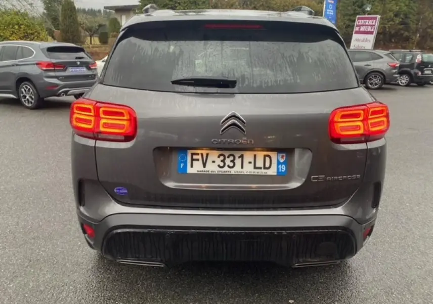 Vue arrière d'un Citroën C5 Aircross gris platinium avec feux allumés et hayon électrique mains libres visible.