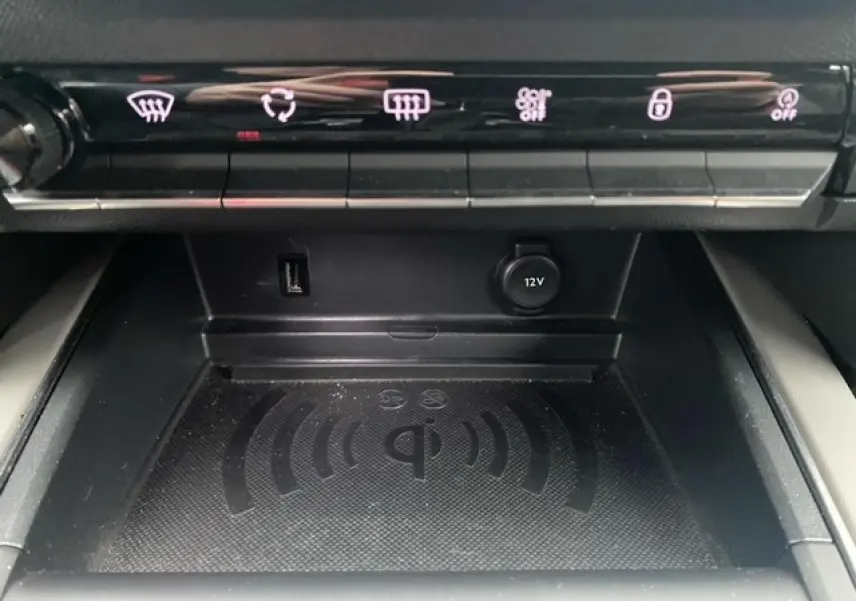 Gros plan sur la zone de recharge sans fil Qi et les commandes de climatisation du Citroën C5 Aircross gris platinium.