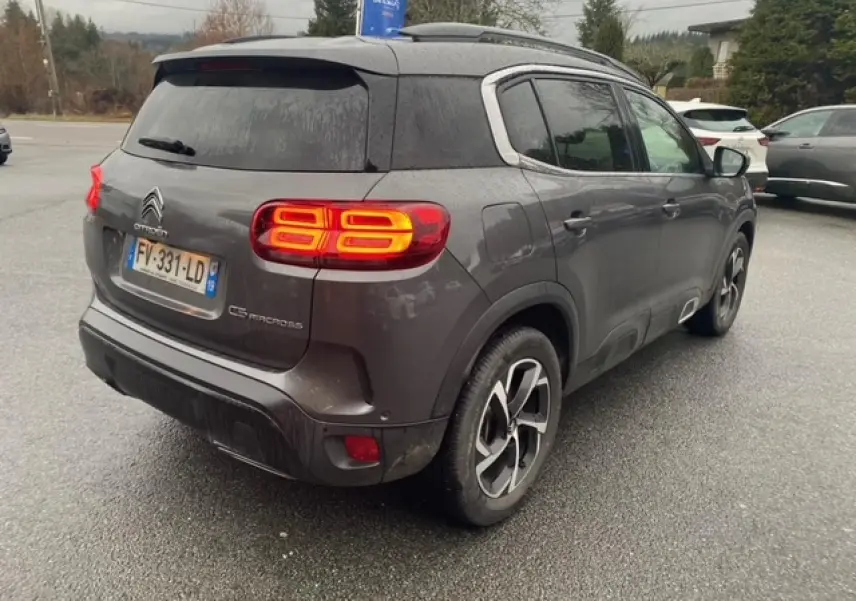 Vue 3/4 arrière droite d'un Citroën C5 Aircross gris platinium avec feux arrière allumés et jantes alliage 18 pouces.