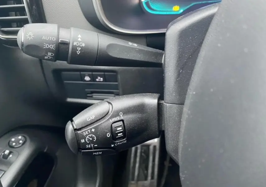 Gros plan sur les commandes au volant du Citroën C5 Aircross gris platinium, montrant les leviers de régulateur et feux.