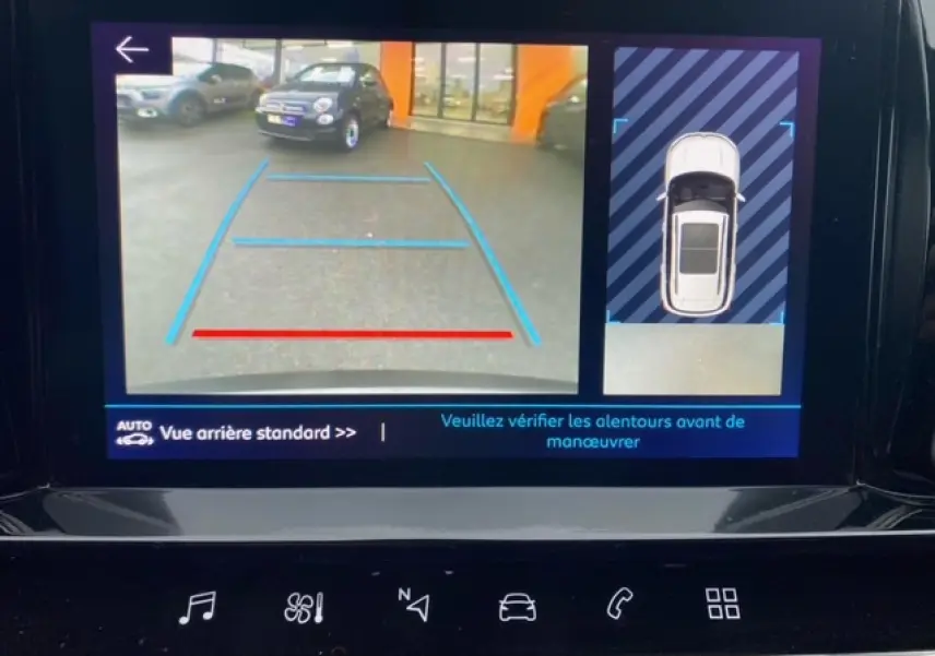 Écran de caméra de recul montrant une voiture grise en 3/4 arrière avec lignes de guidage bleues et rouges.