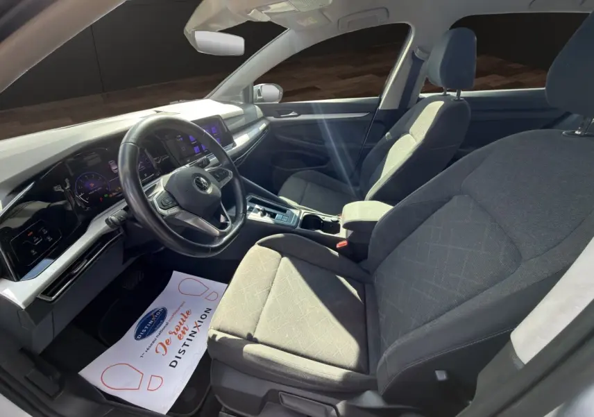 Intérieur avant droit de la Volkswagen Golf gris clair 2022, avec tableau de bord numérique et volant cuir multifonctions.