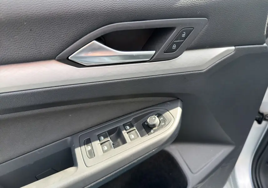 Détail de la porte côté conducteur de la Volkswagen Golf 2022 gris clair, avec commandes des vitres et serrure intégrée.