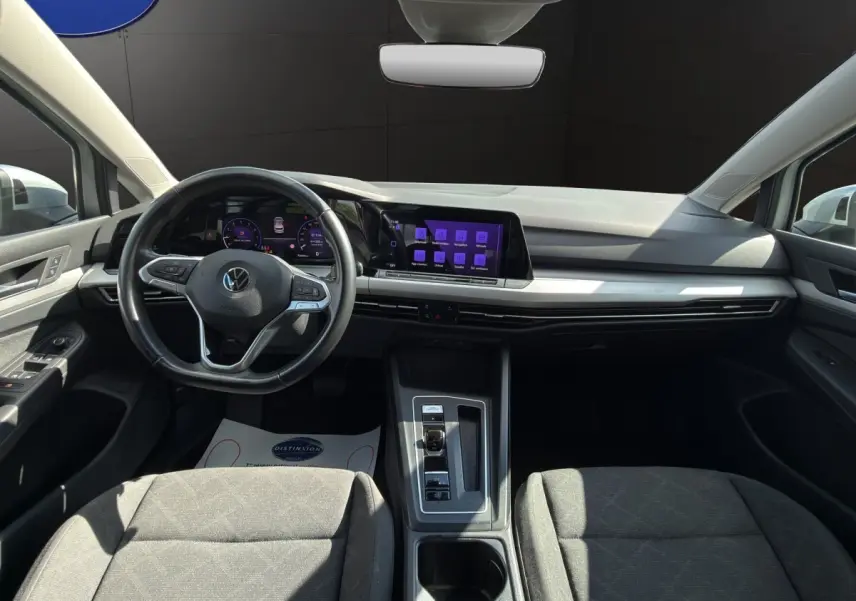 Vue intérieure avant de la Volkswagen Golf 1.0 ETSI gris clair, avec tableau de bord numérique et écran tactile central.