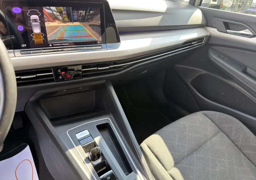 Vue intérieure côté passager de la Volkswagen Golf grise avec écran de recul et console centrale moderne.