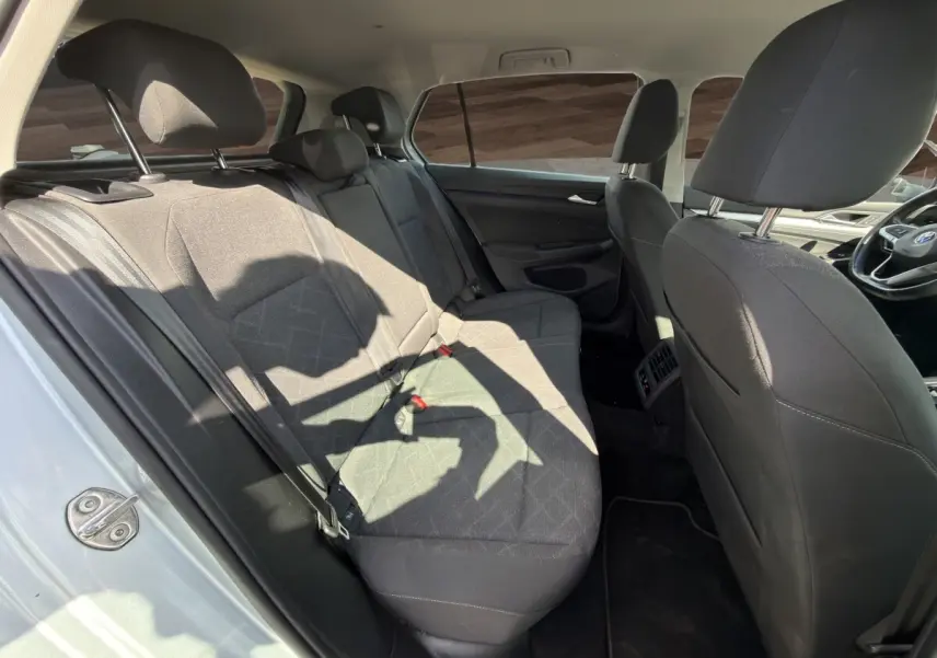 Vue intérieure côté gauche montrant la banquette arrière noire et les sièges avant d'une Volkswagen Golf gris clair 2022.