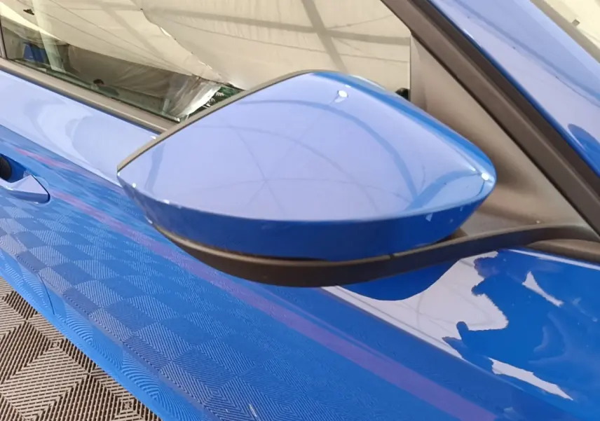 Rétroviseur côté gauche bleu vif de la Skoda Octavia 2024, avec portière et poignée partiellement visibles.