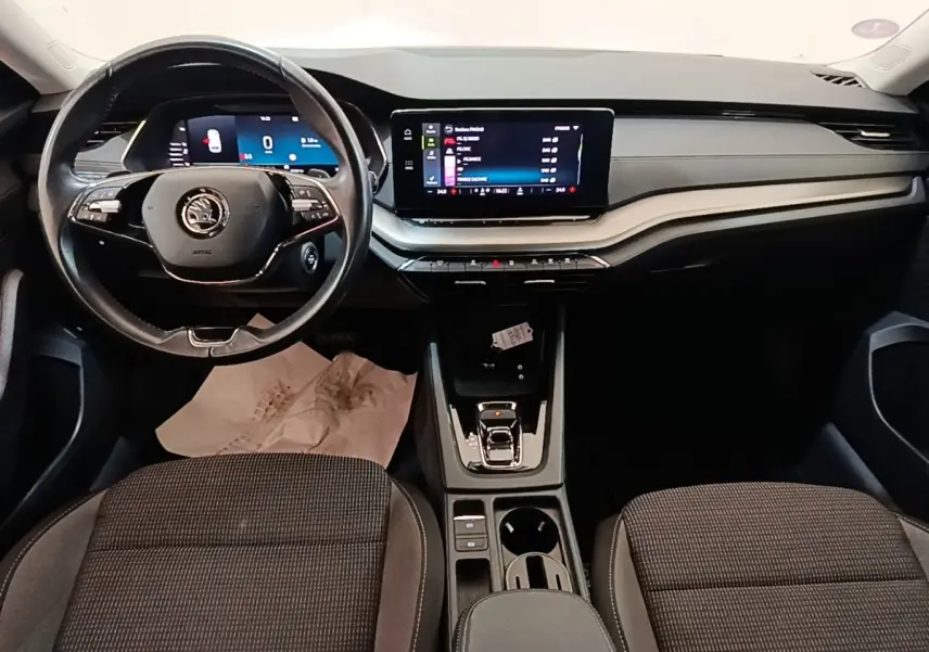 Vue intérieure avant de la Skoda Octavia 2024, tableau de bord noir avec écran tactile central et volant multifonctions.