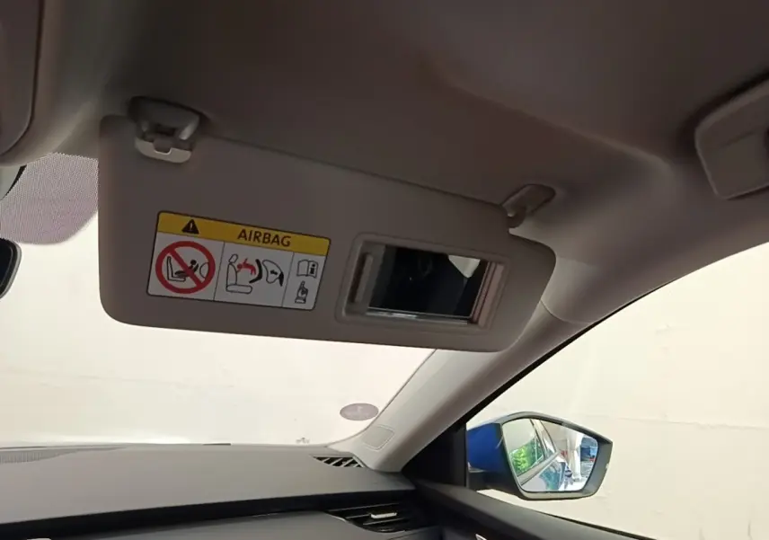 Intérieur côté passager d’une Skoda Octavia 2024, visière pare-soleil beige avec miroir et avertissement airbag visible.