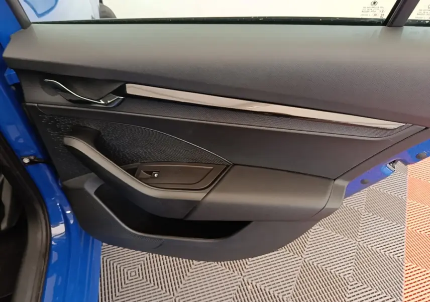 Vue intérieure de la porte côté gauche d’une Skoda Octavia 2024 bleue avec garniture noire et insert chromé.