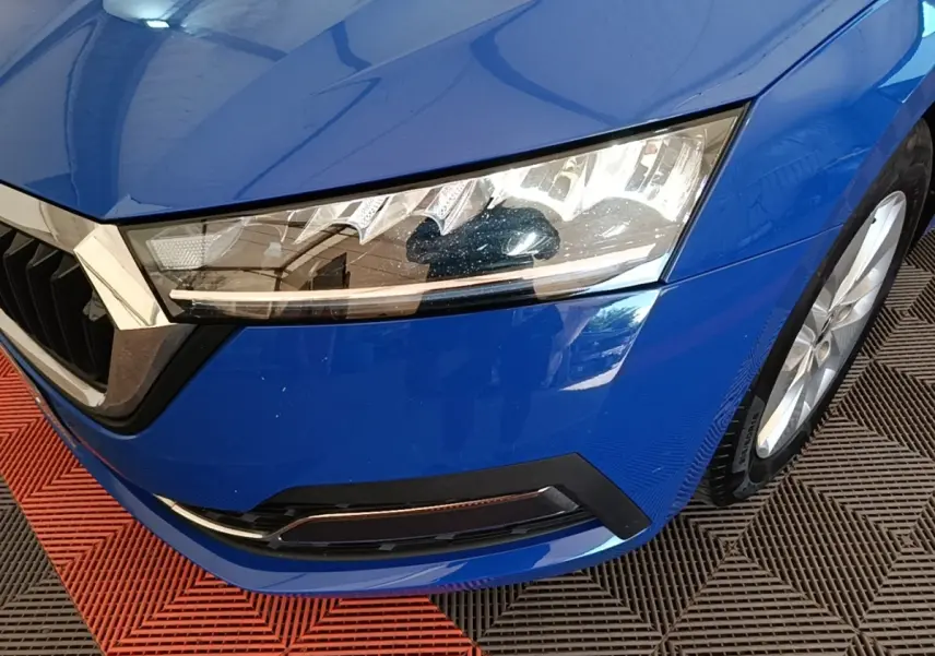 Gros plan sur l'avant droit bleu vif d'une Skoda Octavia 2024, mettant en valeur le phare LED et la calandre chromée.