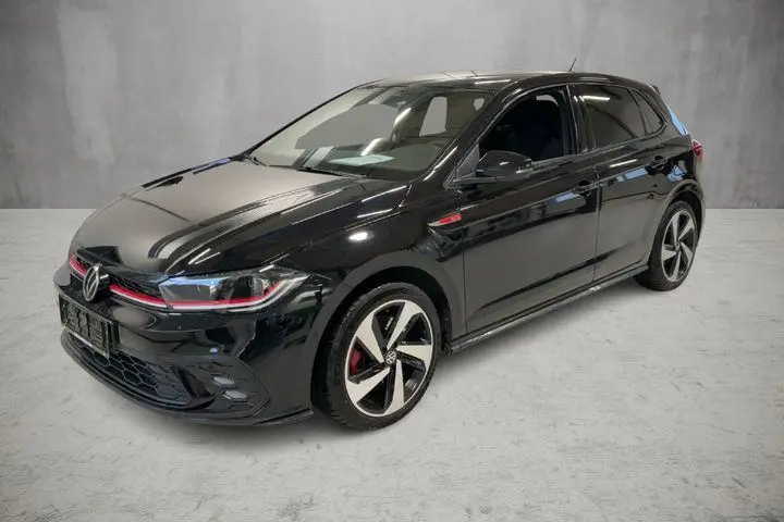 Vue 3/4 avant droite d'une Volkswagen Polo GTI noire 2024 avec jantes alliage 17 pouces et détails rouges sur la calandre.