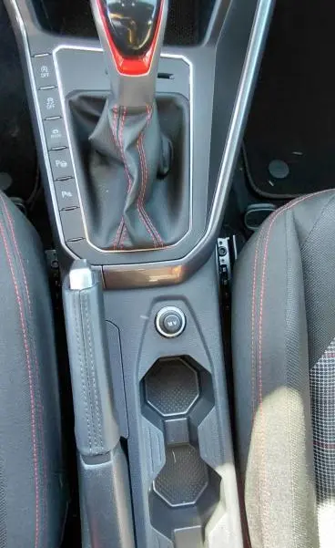 Vue plongeante sur la console centrale de la Volkswagen Polo GTI 2024 noire, avec levier de vitesse DSG7 et coutures rouges sport.