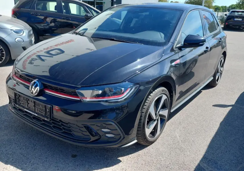 Volkswagen Polo GTI noire vue 3/4 avant droit, avec jantes alliage 17 pouces et signature lumineuse rouge distinctive.