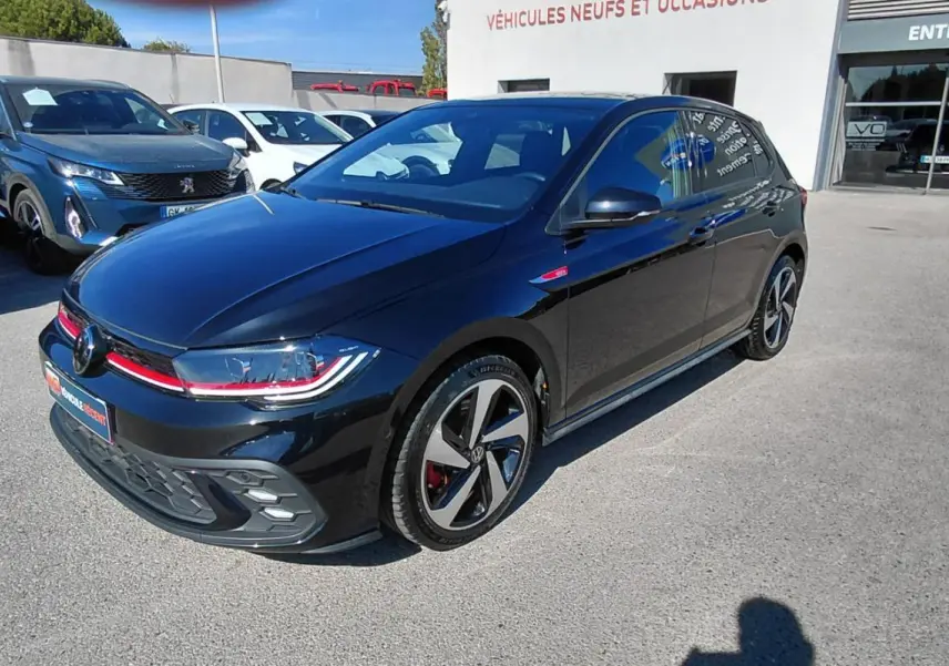 Volkswagen Polo GTI noir vue 3/4 avant droit, jantes alliage 17 pouces et bande rouge distinctive sur calandre.
