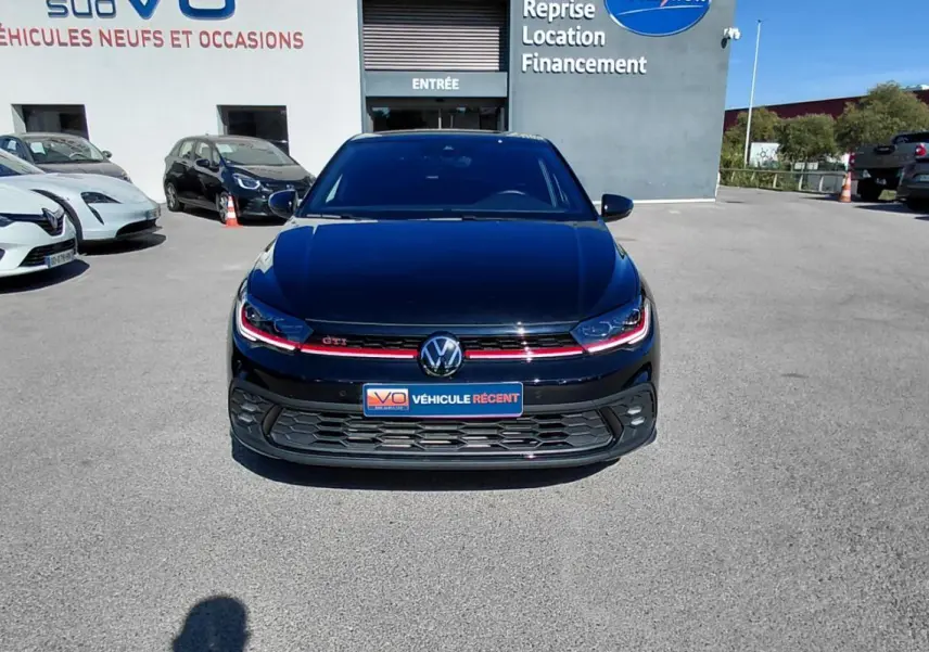 Volkswagen Polo GTI noire vue de face, avec signature lumineuse rouge et calandre sportive en concession.