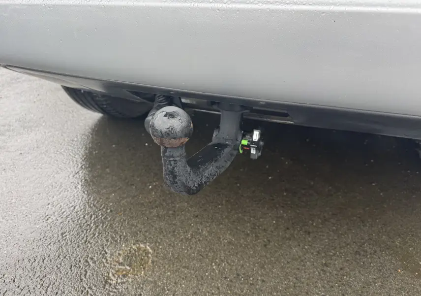 Gros plan sur l'attelage d'une Jeep Compass gris 2023, visible sous le pare-chocs arrière sur sol humide.