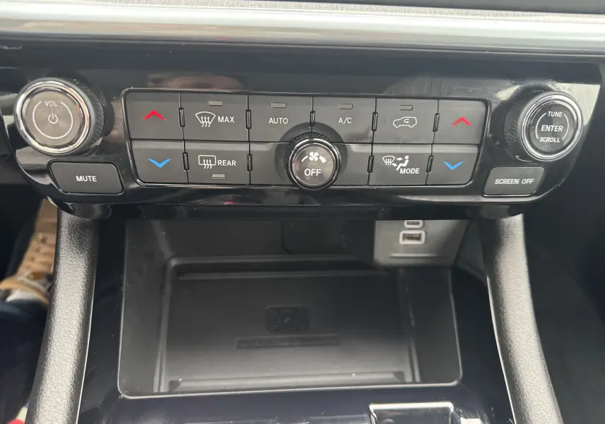 Panneau de commande de climatisation et audio du Jeep Compass 2023, avec boutons noirs et molette argentée.