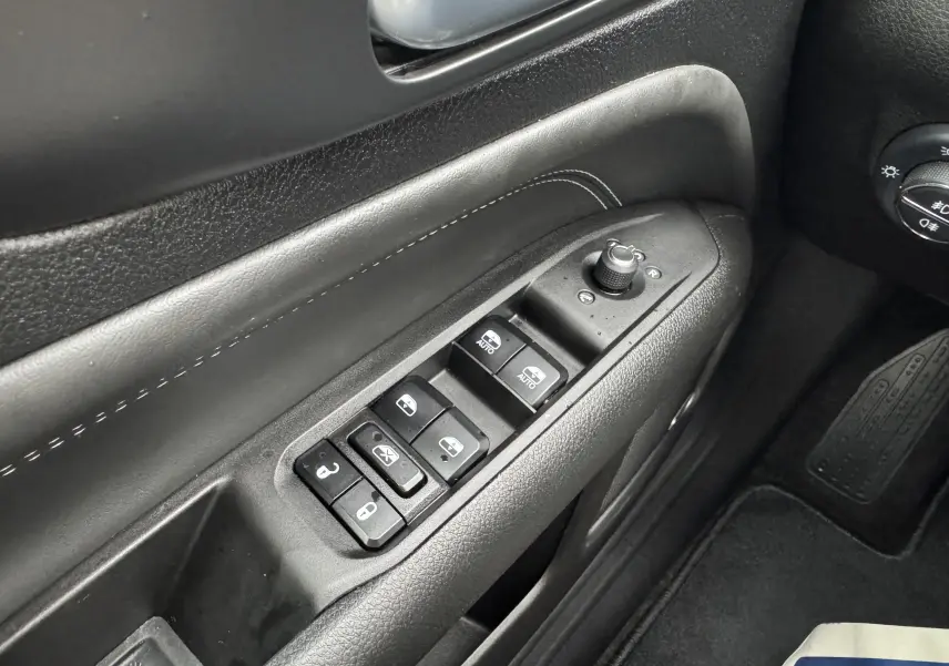 Gros plan sur les commandes de lève-vitres et réglage des rétroviseurs côté gauche d'une Jeep Compass gris 2023.