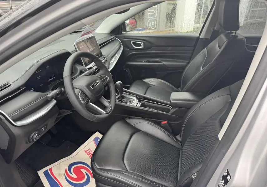 Vue intérieure côté conducteur du Jeep Compass 2023 gris, montrant sièges cuir noirs et tableau de bord moderne avec écran tactile central.