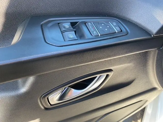 Gros plan sur la poignée intérieure et les commandes de vitre côté gauche d’un Renault Trafic Fourgon blanc 2023.