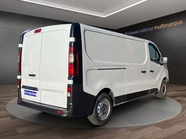 Vue 3/4 arrière droite d’un Renault Trafic Fourgon blanc 2023 avec détails noirs sur les pare-chocs et portes arrière.
