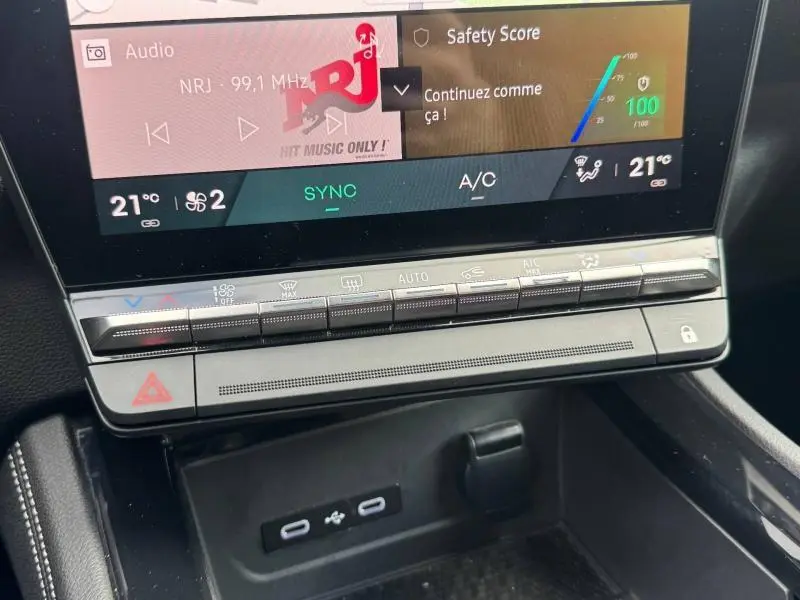 Gros plan sur la console centrale avec écran tactile et commandes climatisation du Renault Austral rouge, version hybride 2025.