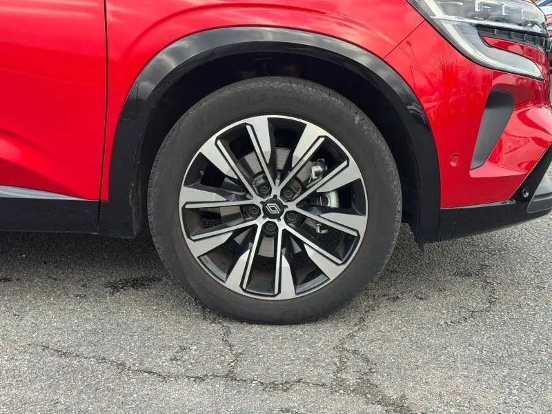 Gros plan sur la roue avant droite avec jante alu noire et argentée du Renault Austral rouge flamme 2025.