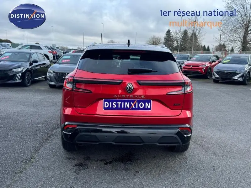Vue arrière d'un Renault Austral rouge flamme avec feux LED et toit noir sur un parking extérieur.