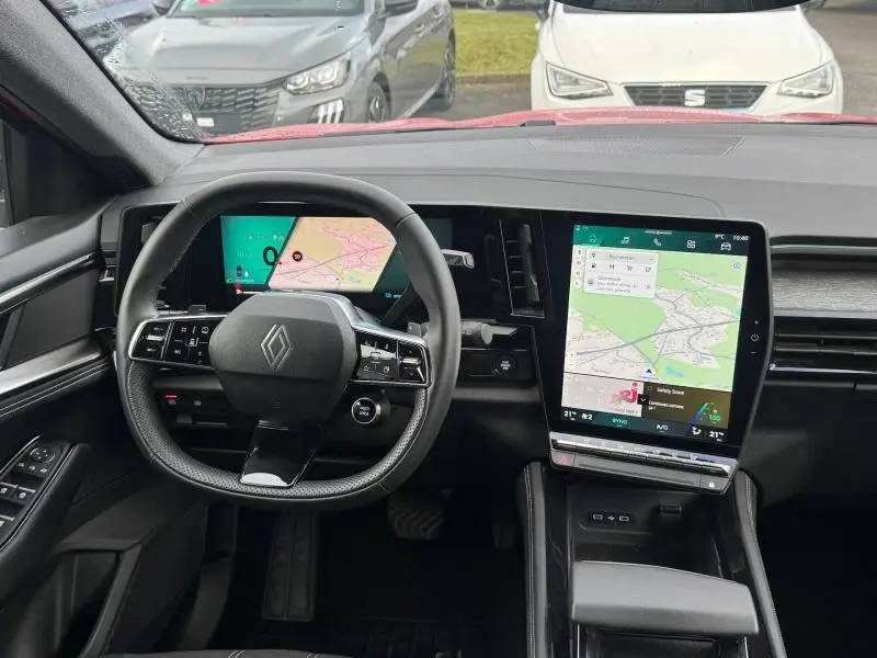 Vue intérieure du tableau de bord du Renault Austral rouge, avec volant multifonction et grand écran tactile vertical.