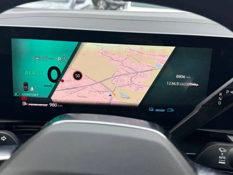 Vue rapprochée de l'écran numérique du tableau de bord du Renault Austral rouge, affichant la navigation GPS et les informations de conduite.