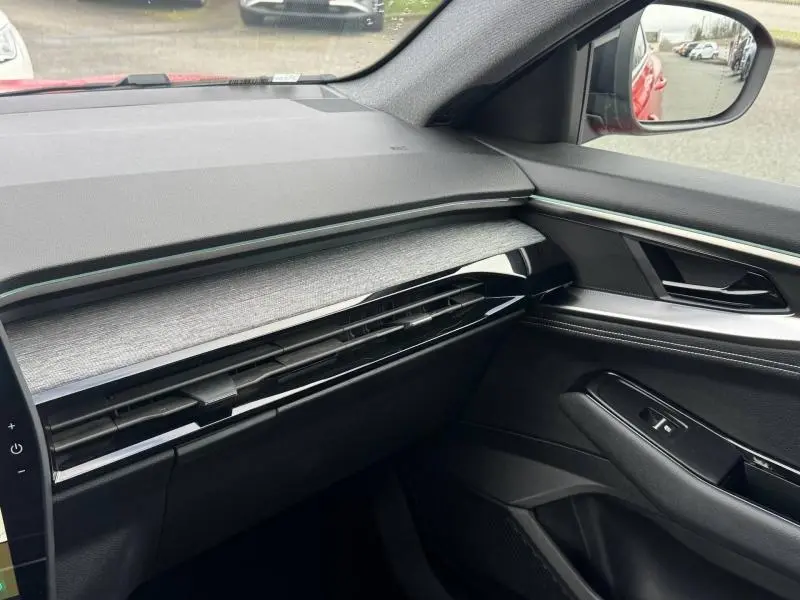 Vue intérieure côté passager du tableau de bord et porte avec finitions noires et grises du Renault Austral rouge 2025.