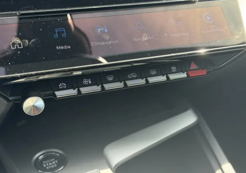 Vue rapprochée de la console centrale de la Peugeot 308 Hybrid 2025, montrant l'écran tactile et les boutons de commande.