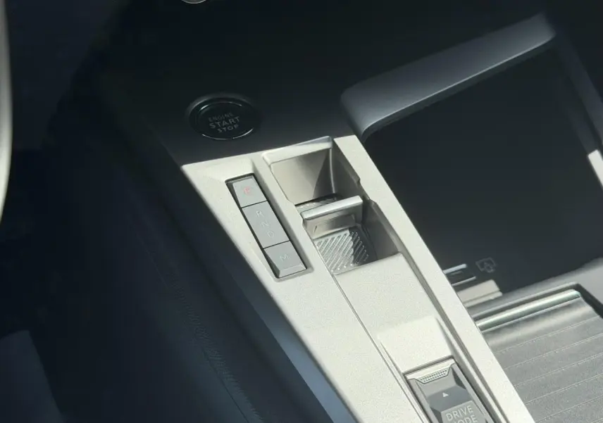 Gros plan sur la console centrale gris clair de la Peugeot 308 Hybrid avec boutons de boîte auto et bouton start/stop.
