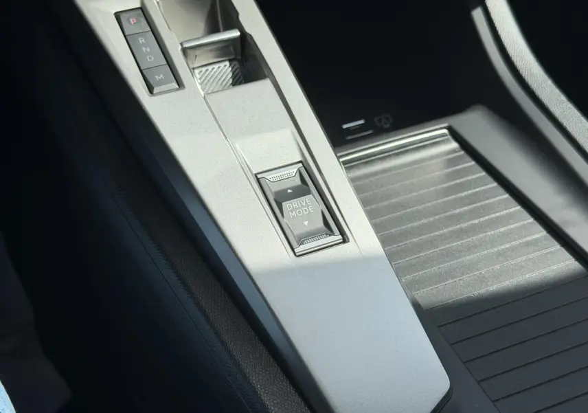 Gros plan sur la console centrale grise de la Peugeot 308 Hybrid avec sélecteur de mode de conduite et levier de vitesses automatique.