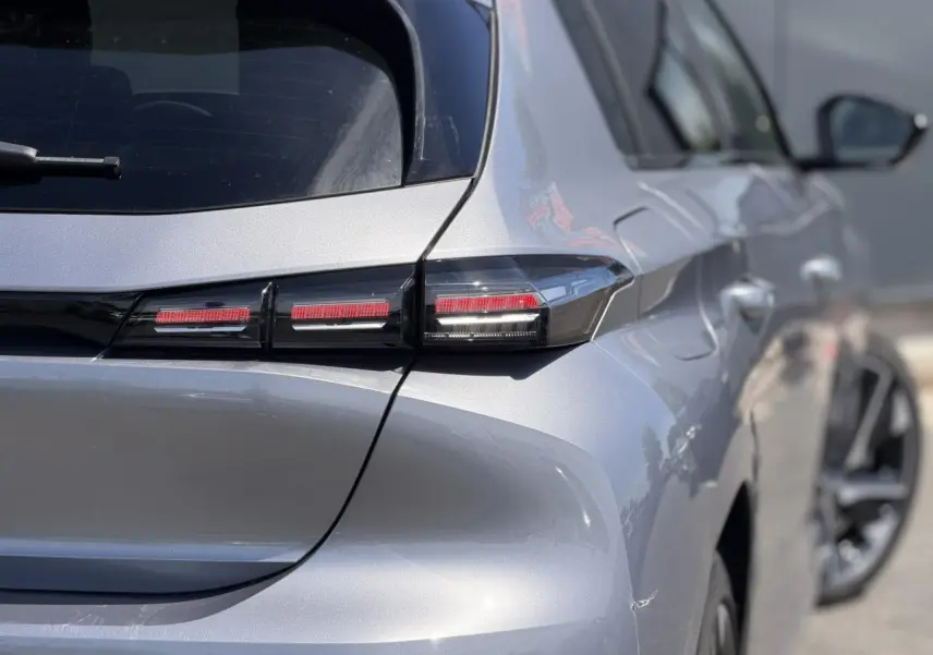 Vue arrière droite de la Peugeot 308 Hybrid 145 gris Artense, mettant en valeur ses feux arrière LED distinctifs.