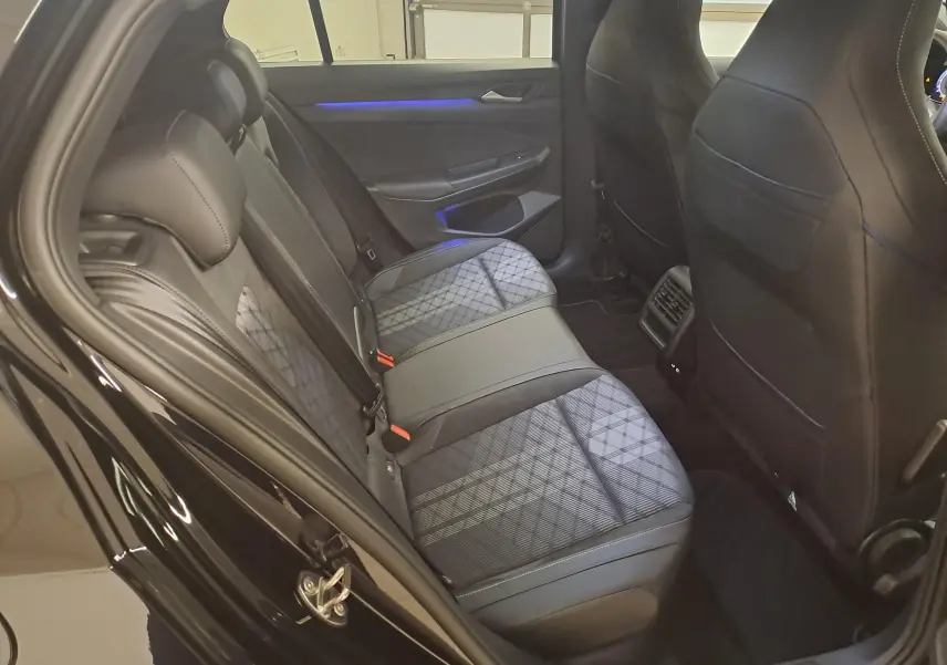Vue intérieure arrière côté gauche de la Volkswagen Golf 2.0 TDI 150 DSG7 R Line 2024 avec sièges tissu et cuir noirs à motif géométrique.