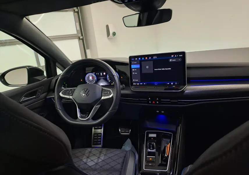 Vue intérieure avant de la Volkswagen Golf 2.0 TDI 150 DSG7 R Line 2024, tableau de bord noir avec écran tactile et éclairage bleu.