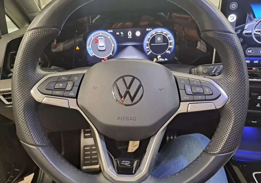 Vue rapprochée du volant perforé noir avec logo Volkswagen et tableau de bord numérique de la Golf 2.0 TDI 2024.