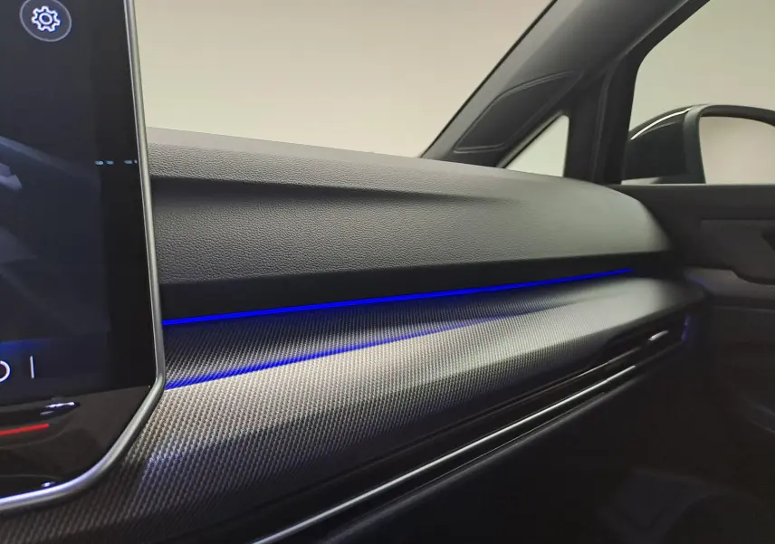 Tableau de bord intérieur côté passager de Volkswagen Golf 2.0 TDI 150 DSG7 R LINE 2024 avec éclairage d'ambiance bleu.