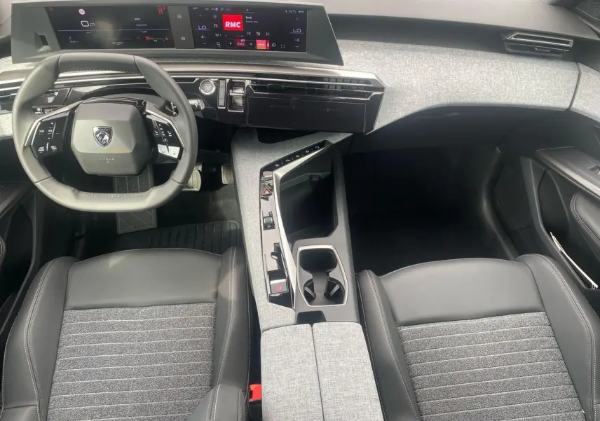 Vue intérieure avant du Peugeot 3008 2025, volant cuir multifonction et console centrale avec accoudoir gris clair.