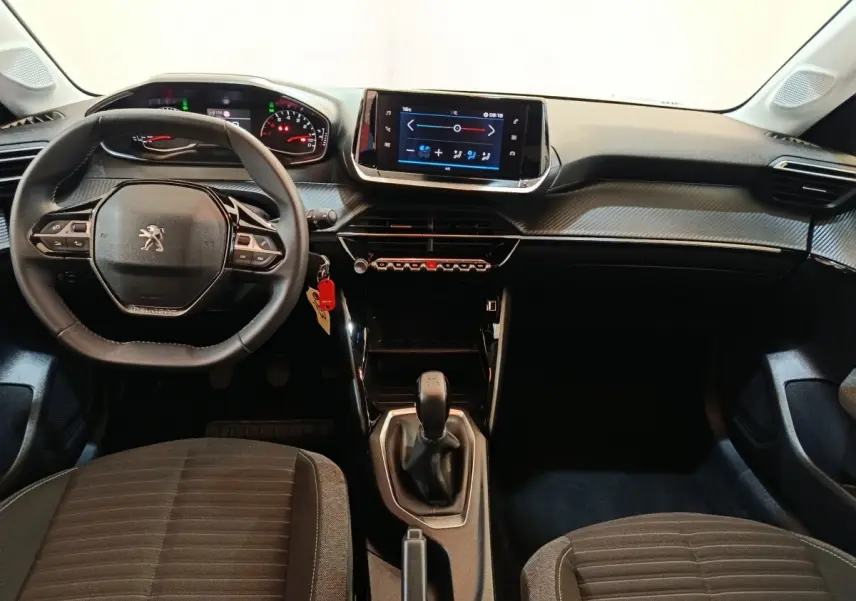 Vue intérieure avant du tableau de bord de la Peugeot 208 blanche, volant cuir multifonctions et écran tactile central.