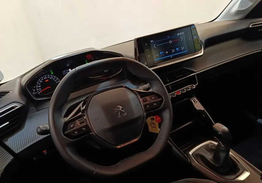 Vue intérieure centrée sur le volant cuir multifonctions et la console centrale avec écran tactile de la Peugeot 208 2023.