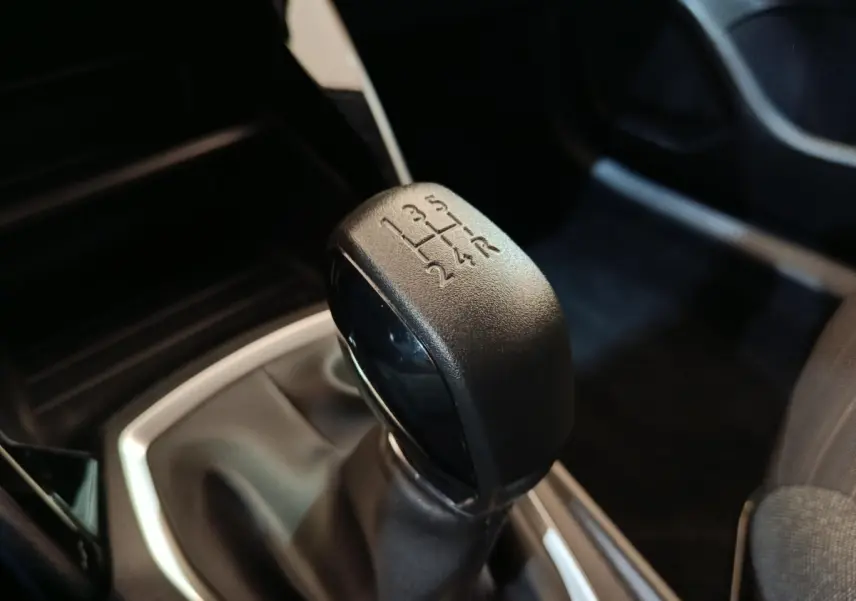 Le levier de vitesses manuel noir de la Peugeot 208 PureTech 75 S&S Style, vue rapprochée de l'intérieur.