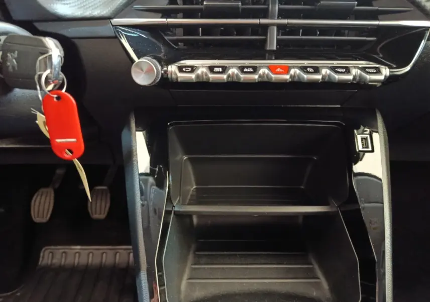 Vue rapprochée de la console centrale noire d’une Peugeot 208 PureTech 75 S&S Style avec clés et pédales visibles.